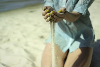 Woman in Green Button-up Top Scooping Beach Sand With Both Hands