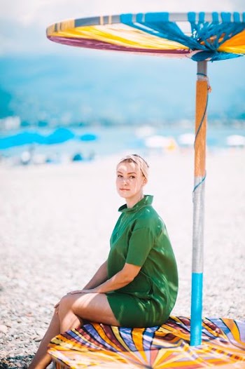 woman in green dress seating under umbrella