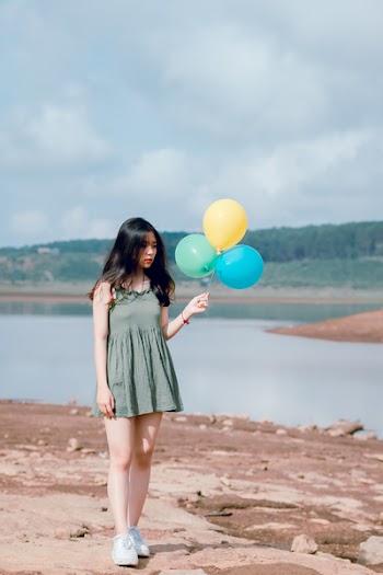 Woman in Green Sleeveless Dress Holding Balloons