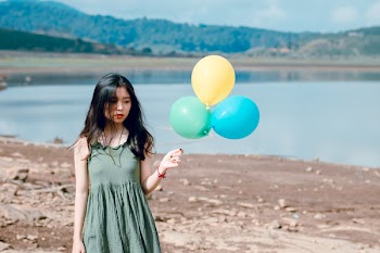 Woman in Green Sleeveless Dress Holding Three Balloons
