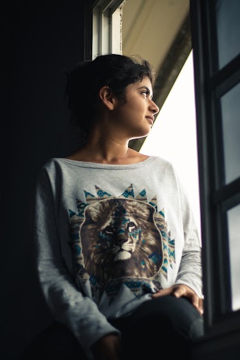 Woman In Grey Lion Print Sweater Looking Out A Window