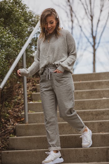 Woman In Grey Sweater And Grey Bottoms Walking Down Stairs