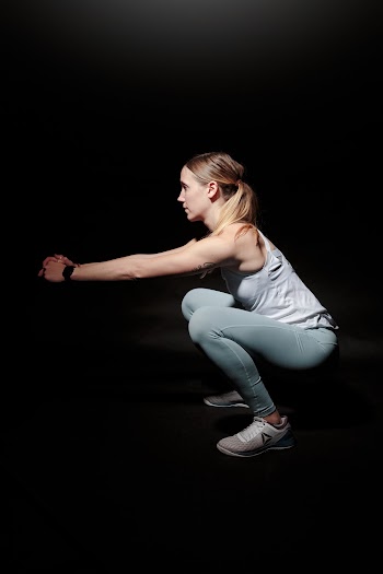 Woman In Gym Wear Doing Squats 
