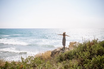 Woman in Long Dress Standing on Rock Near Body of Water