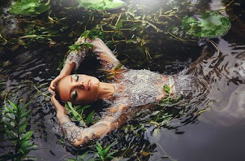 Woman In Long Sleeved Dress Surrounded By Water Plants