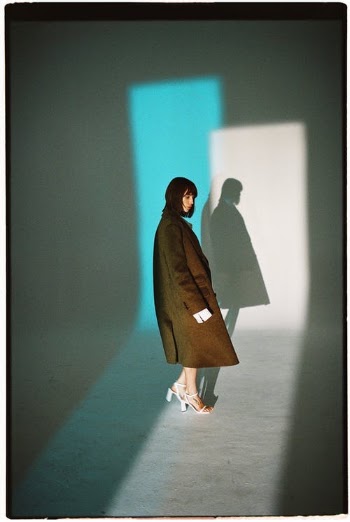 Woman in Man's Trench Coat Standing in Light Coming from Door · Free Stock Photo