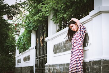 Woman In Multi-colored Dress Standing In Front Of White Painted Wall