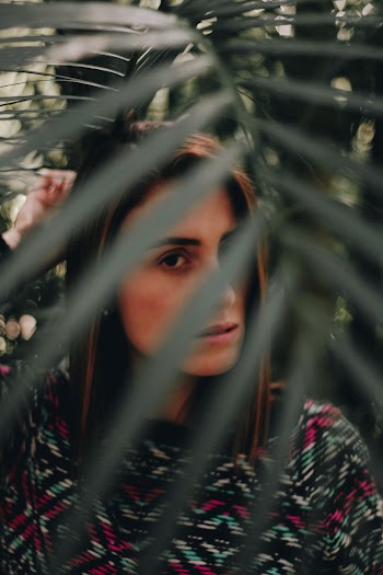 Woman in Multicolored Shirt Standing Under Palm Fronds