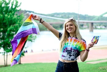 Woman in Multicolored Tie Dyed T-shirt and Black Denim Jeans Waving Flaglet