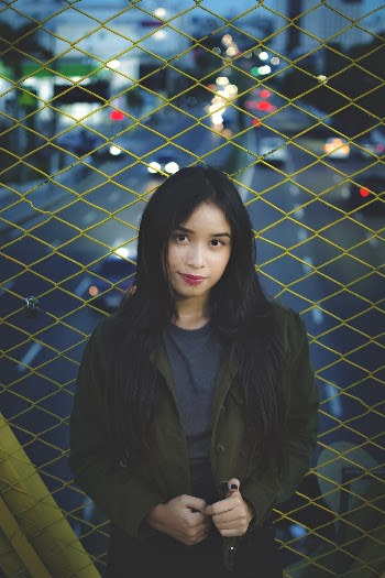 Woman in Olive-green Jacket Beside Fence