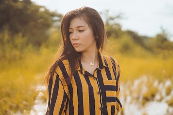Woman in Orange and Black Striped Collared Shirt on Grass Field