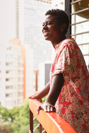 Woman in Orange and Green Floral Dress Standing on Terrace