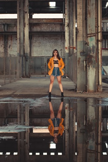 Woman in Orange Blazer Standing in Front of Water Puddle