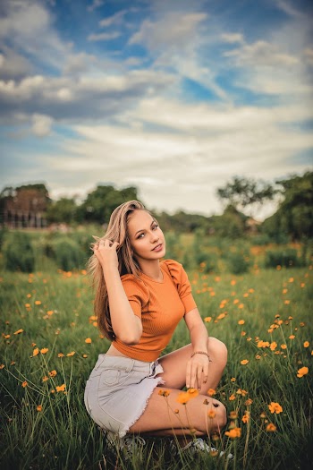 Woman in Orange Crew-neck Top and Gray Shorts on a Grassfield