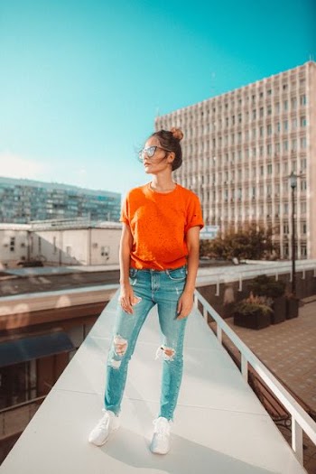 woman in orange crew-neck top standing footbridge