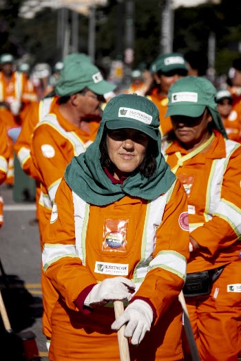 Woman in Orange Jumpsuits and Green Cap Cleaning the Street