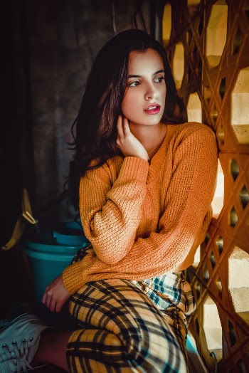 Woman In Orange Knit Sweater Leaning On Wall
