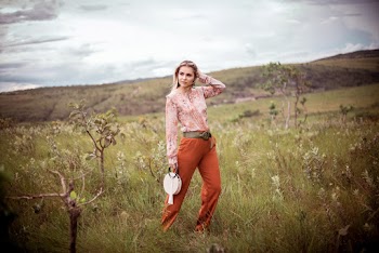 Woman In Orange Pants Standing On Grass Field