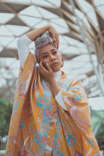 Woman in Orange, Red, and Blue Floral Poncho Dress Holding Her Head