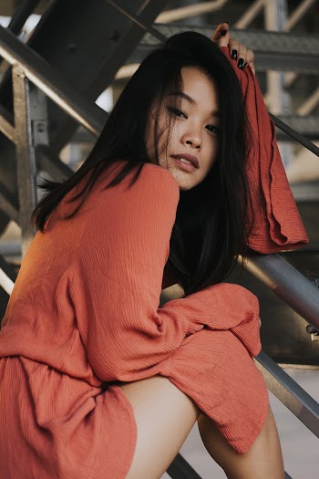 Woman in orange top sitting down 