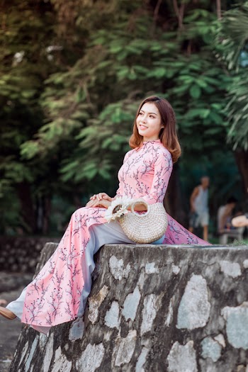 Woman in Pink Maxi Dress Sitting on Gray Wall