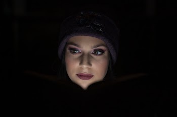 Woman in Purple Beanie While Reading In The Dark