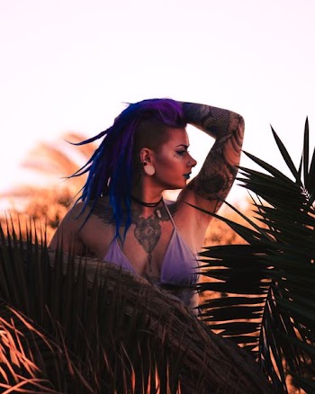 woman in purple bikini top standing near plant while holding her head