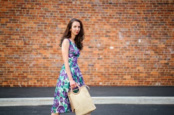 Woman in Purple Floral Dress With Beige Handbag