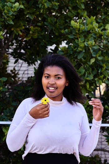 Woman in Purple Turtleneck Sweatshirt Holding Yellow Petaled Flower