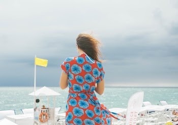 Woman in Red and Blue Floral Dress Standing Near Body of Water