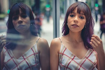 Woman in Red, Brown, and White Plaid Leaning on Glass Wall