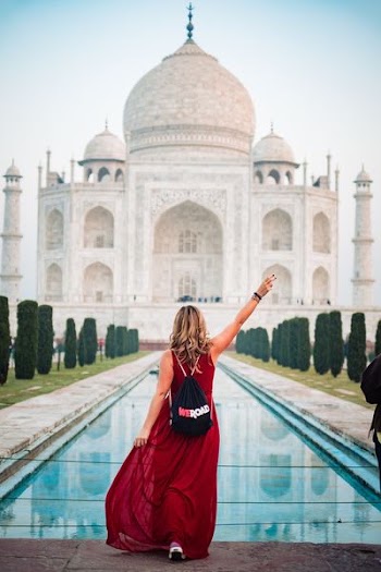 woman in red dress standing in front of Taj Mahal
