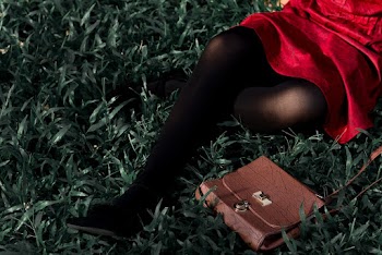 Woman in Red Dress With Black Stockings Sitting on a Grass 