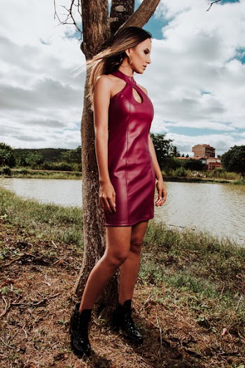 Woman in Red Leather Halter Keyhole Midi Dress Leaning on Brown Tree