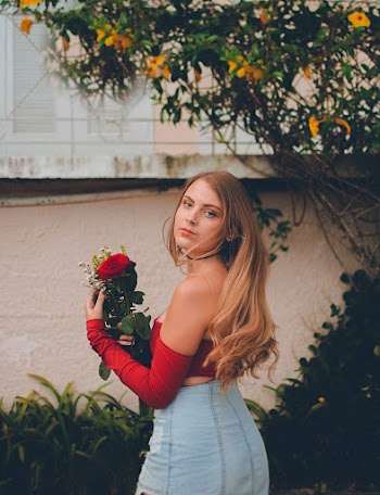Woman in Red Off-shoulder Top Holding Flower