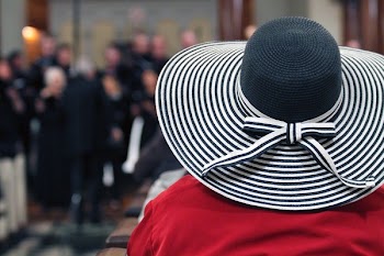 Woman in Red Shirt and Black and White Stripes Sunhat Surrounded by People