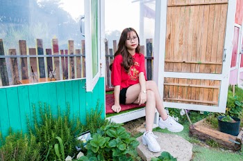Woman in Red Shirt and Black Short Shorts Sitting on Wooden Floor