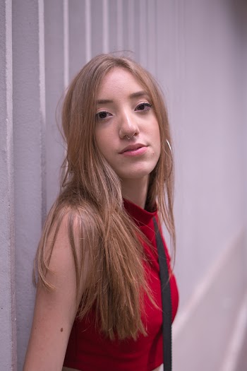Woman in Red Sleeveless Top Leaning on Wall