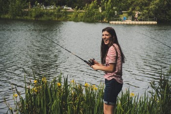 Woman in Red Striped Shirt and Blue Denim Shorts Holding Fishing Rod