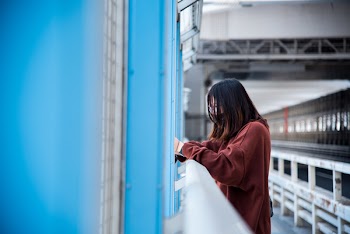 Woman in Red Sweater Leaning on White Steel Railing
