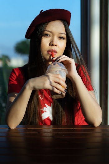 Woman in Red Top and Beret Sipping Straw