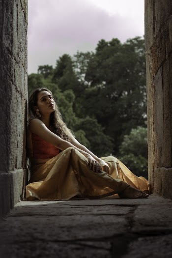 Woman in Red Top and Orange Maxi Skirt Sitting on the Floor