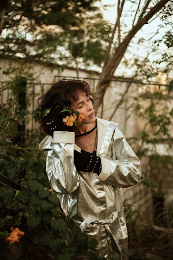 Woman in Silver Coat Holds Yellow Flowering Plant