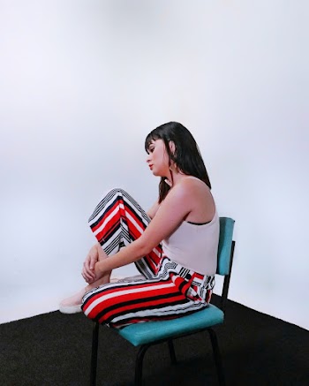 Woman in Spaghetti Strap Top and Pinstriped Pants Sitting on Chair