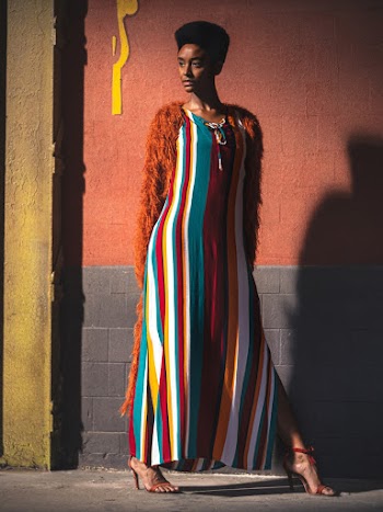 Woman in Striped Dress Standing Near Wall