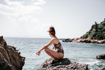 Woman in Swim Suit Sitting on a Rock