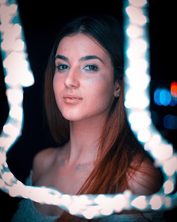 Woman in Teal Scoop-neck Top in Front of String Light