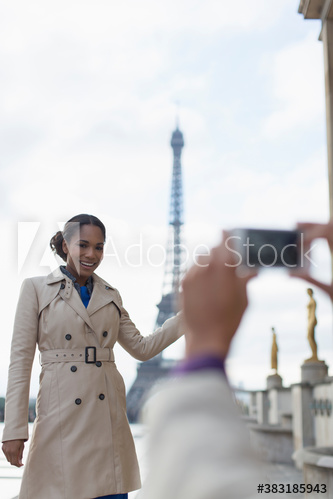 Woman in trench coat posing for photograph in front of Eiffel Tower