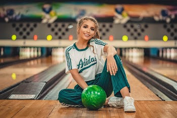 Woman in White Adidas Shirt Sitting Beside Bowling Ball