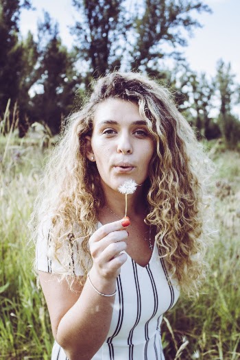 Woman in White and Black Stripe Shirt Holding Dandelion Flower